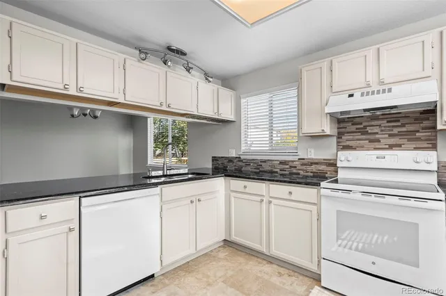 a kitchen with granite countertop white cabinets and white appliances