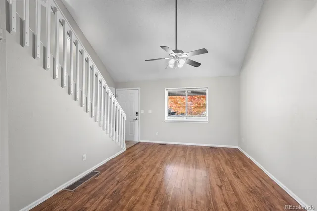 a view of an empty room with wooden floor and a chandelier