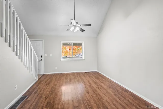 a view of empty room with wooden floor and fan