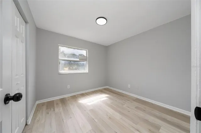 an empty room with a window and wooden floor