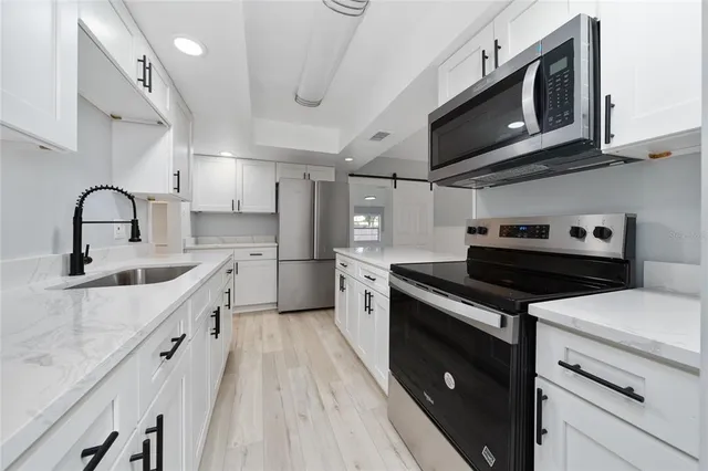 a kitchen with stainless steel appliances granite countertop a sink a stove and a refrigerator