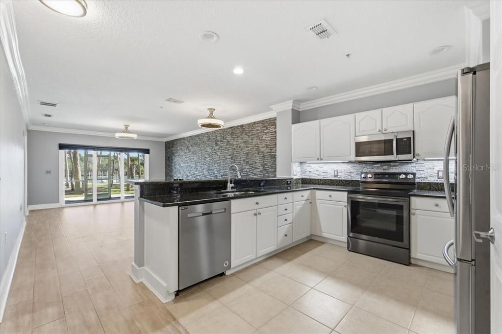 100 Canopy Walk Lane, Unit 112 Palm Coast, FL 32137 - Photo 14 of 62 a kitchen with stainless steel appliances granite countertop a stove top oven a sink dishwasher a refrigerator and white cabinets with wooden floor