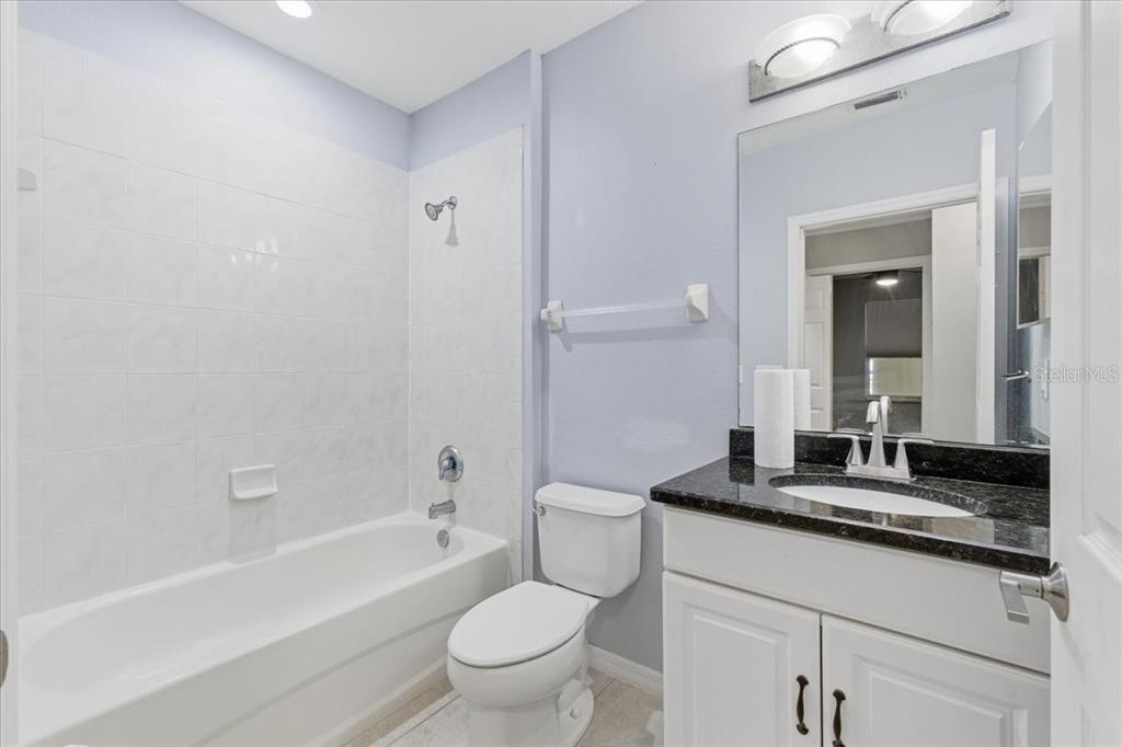 100 Canopy Walk Lane, Unit 112 Palm Coast, FL 32137 - Photo 29 of 62 a bathroom with a granite countertop sink a toilet a mirror and bathtub