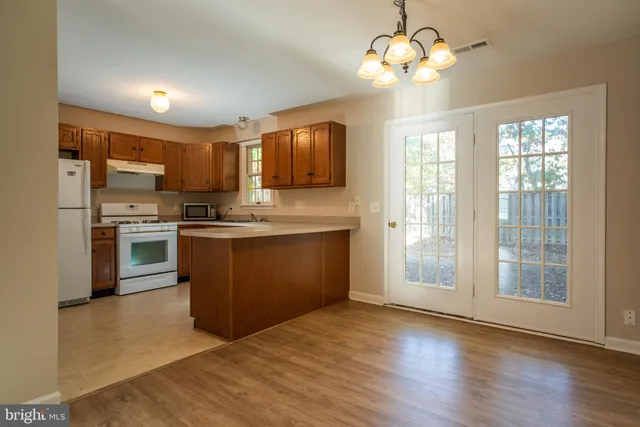 a kitchen with stainless steel appliances granite countertop a stove a sink dishwasher a refrigerator and a dining table with wooden floor