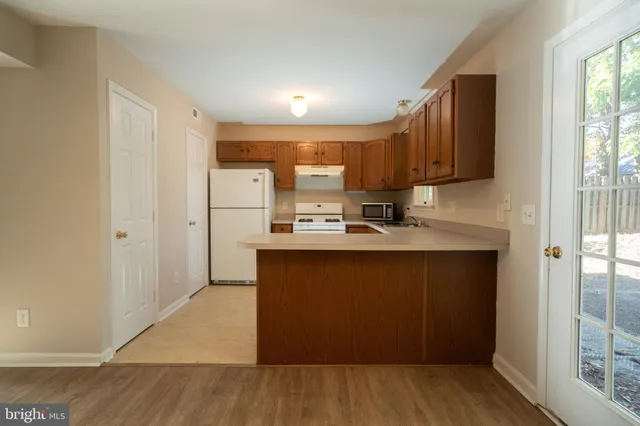 a kitchen with stainless steel appliances granite countertop a refrigerator a sink and a stove with wooden floor