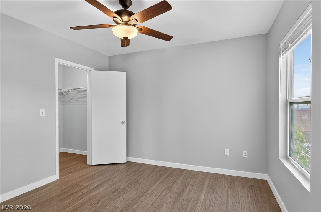 7255 West Sunset Road, Unit 2144 Las Vegas, NV 89113 - Photo 12 of 23 Unfurnished bedroom featuring wood finished floors, a walk in closet, and ceiling fan