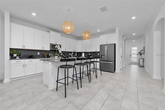 a kitchen with granite countertop a refrigerator and white cabinets