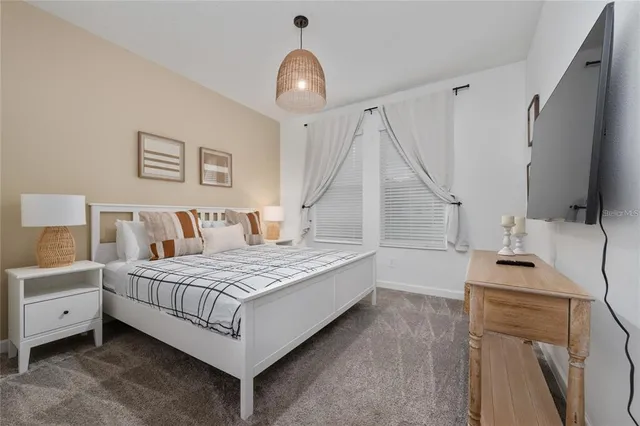 a bedroom with a bed and a flat tv screen on dresser