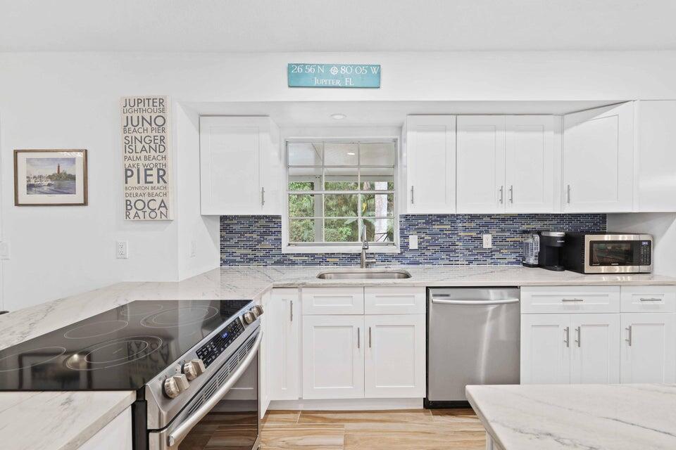 5554 Hibiscus Road Jupiter, FL 33458 - Photo 15 of 70 a kitchen with stainless steel appliances granite countertop a stove and white cabinets