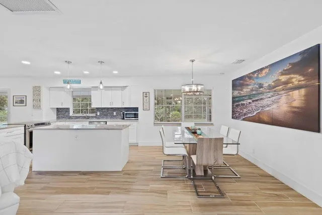 a dining room with wooden floor a chandelier a wooden table and chairs