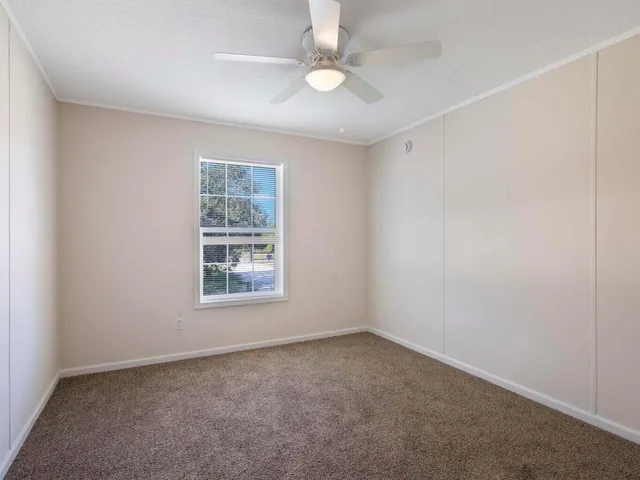 an empty room with a window and a fan
