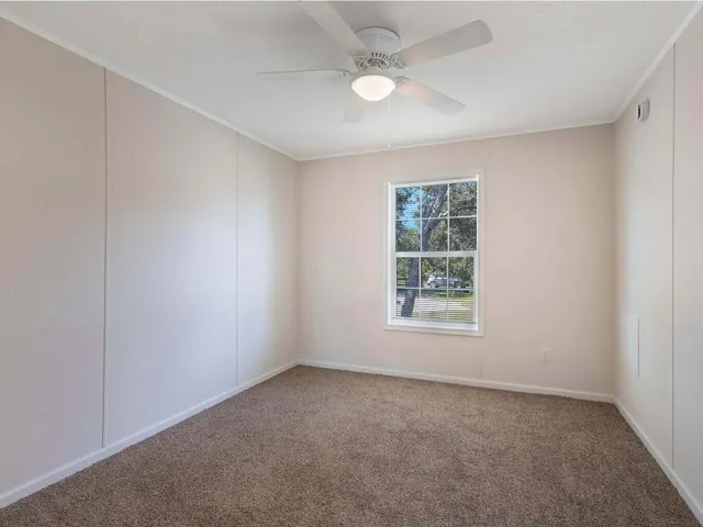 an empty room with a window and a fan
