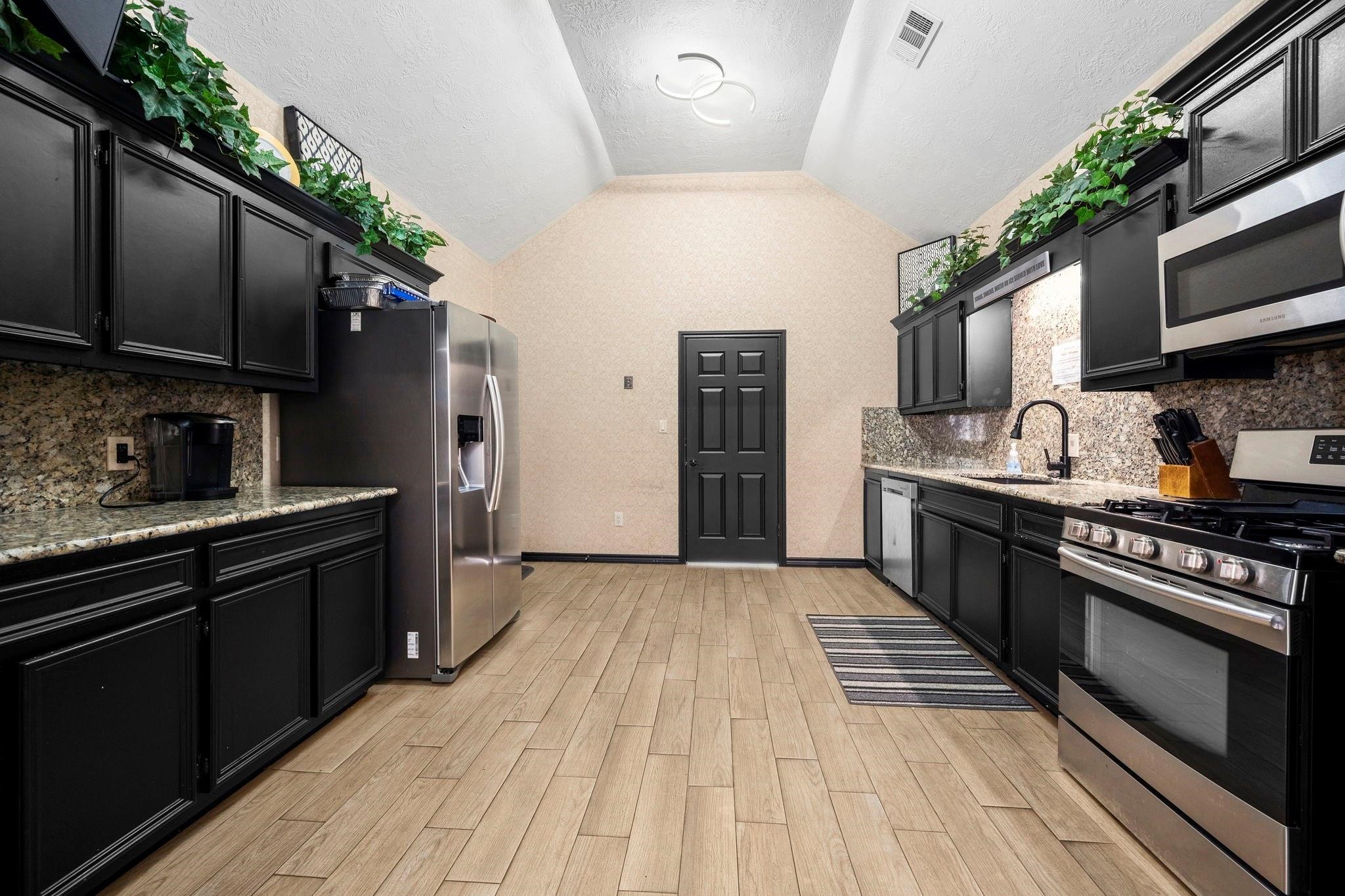 19525 Doerre Road Spring, TX 77379 - Photo 29 of 39 a large kitchen with stainless steel appliances granite countertop a stove a sink dishwasher and a refrigerator with wooden floor