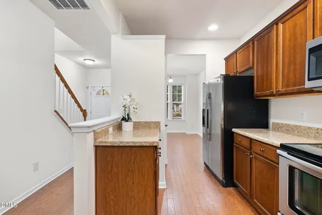 a kitchen with stainless steel appliances granite countertop a refrigerator a stove and a sink