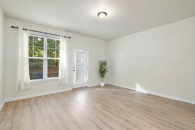 a view of an empty room with wooden floor and a window