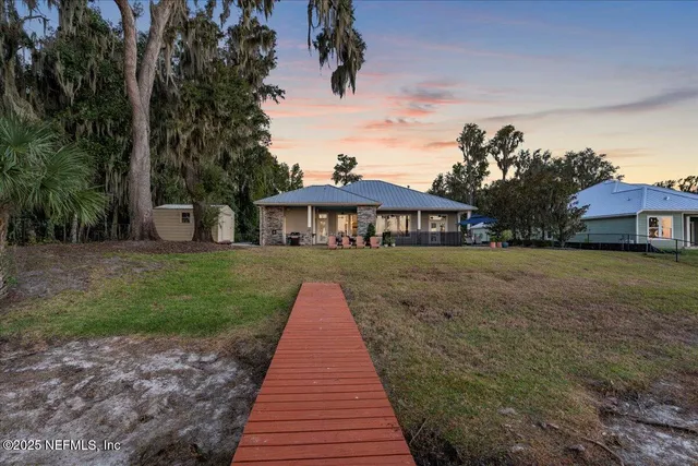a view of a house with a yard and large tree