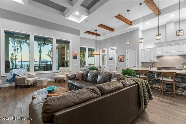 a living room with furniture kitchen view and a wooden floor