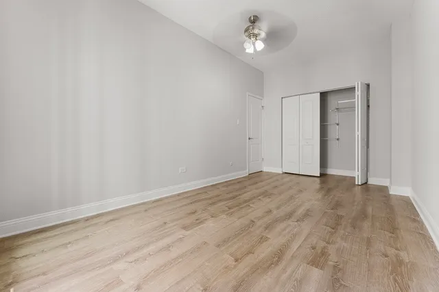 a view of empty room with wooden floor and ceiling fan