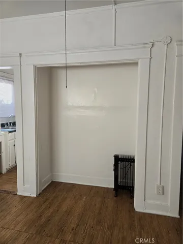 a view of an empty room with wooden floor and closet