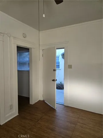 a view of an empty room with wooden floor and a ceiling fan