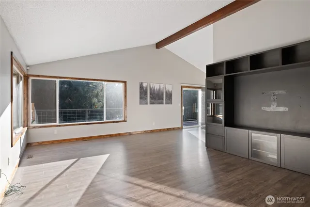 a view of an empty room with a window and wooden floor