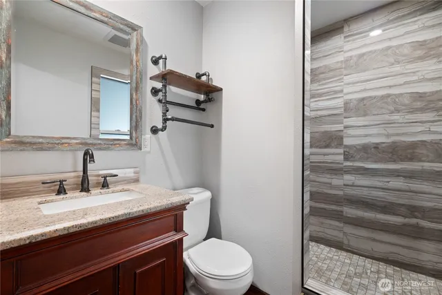 a bathroom with a granite countertop toilet sink and mirror