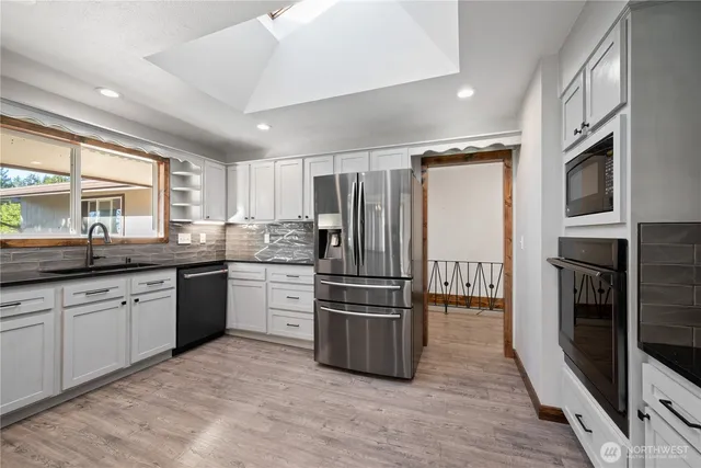 a kitchen with granite countertop stainless steel appliances a sink and a refrigerator