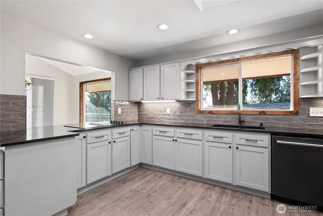 a kitchen with granite countertop sink window and cabinets