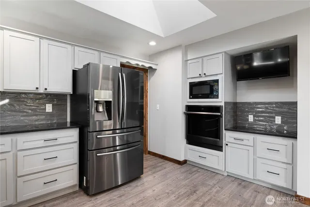 a kitchen with stainless steel appliances white cabinets a refrigerator and a microwave