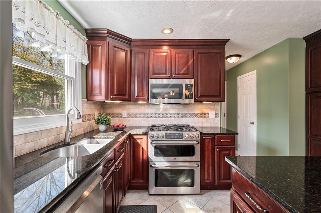 121 Tiffany Ridge Drive Coraopolis, PA 15108 - Photo 5 of 28 The stunning kitchen includes granite countertops accented with a tile backsplash, cherry cabinets and stainless appliances.