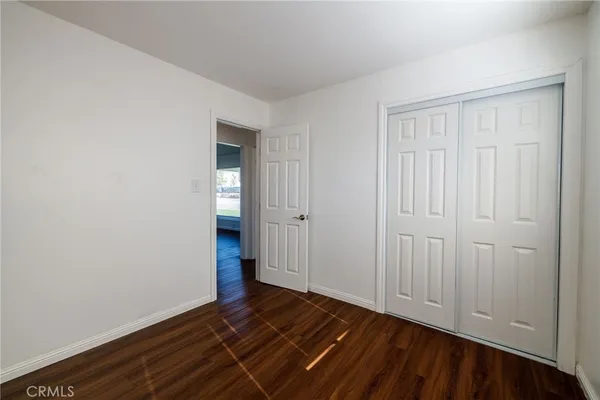 a view of an empty room with wooden floor and closet