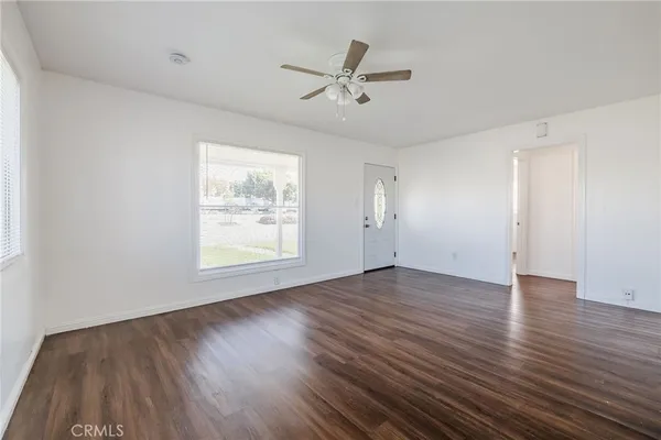 a view of an empty room with wooden floor and a window