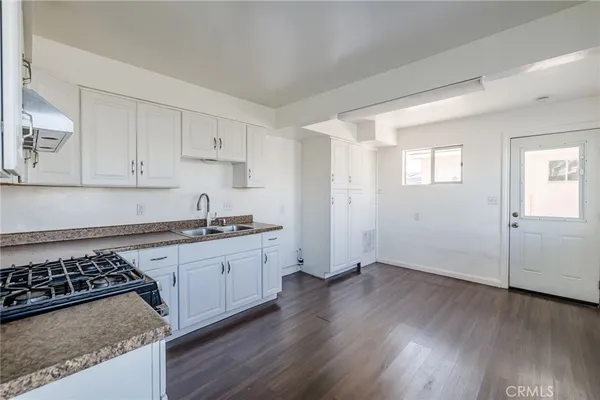 a kitchen with granite countertop a sink stove and cabinets