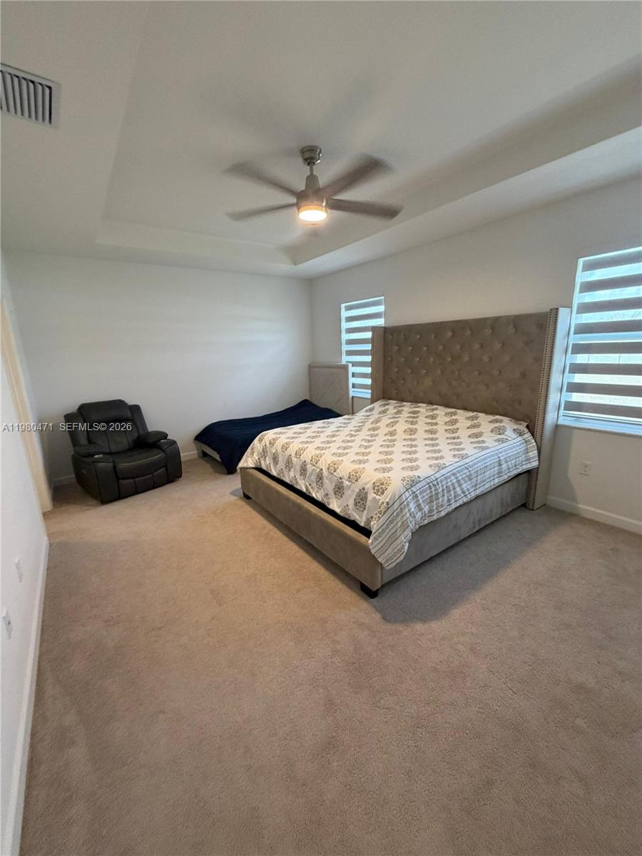 16751 Southwest 291st Terrace, Unit 16751 Homestead, FL 33030 - Photo 13 of 20 a spacious bedroom with a bed and a ceiling fan