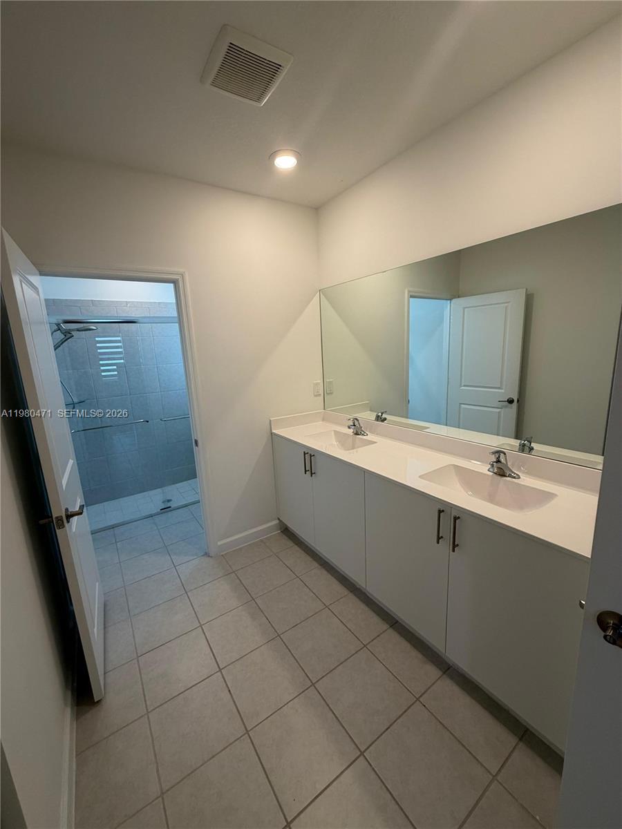 16751 Southwest 291st Terrace, Unit 16751 Homestead, FL 33030 - Photo 15 of 20 a bathroom with a double vanity sink a mirror and a bathtub