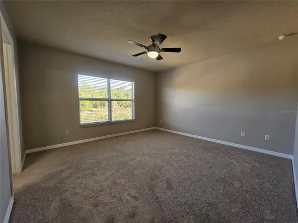 an empty room with windows and fan