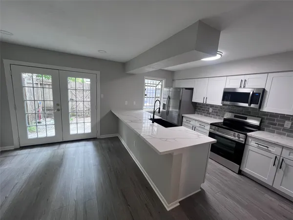 a kitchen with stainless steel appliances a stove top oven a sink dishwasher and a refrigerator with wooden floor