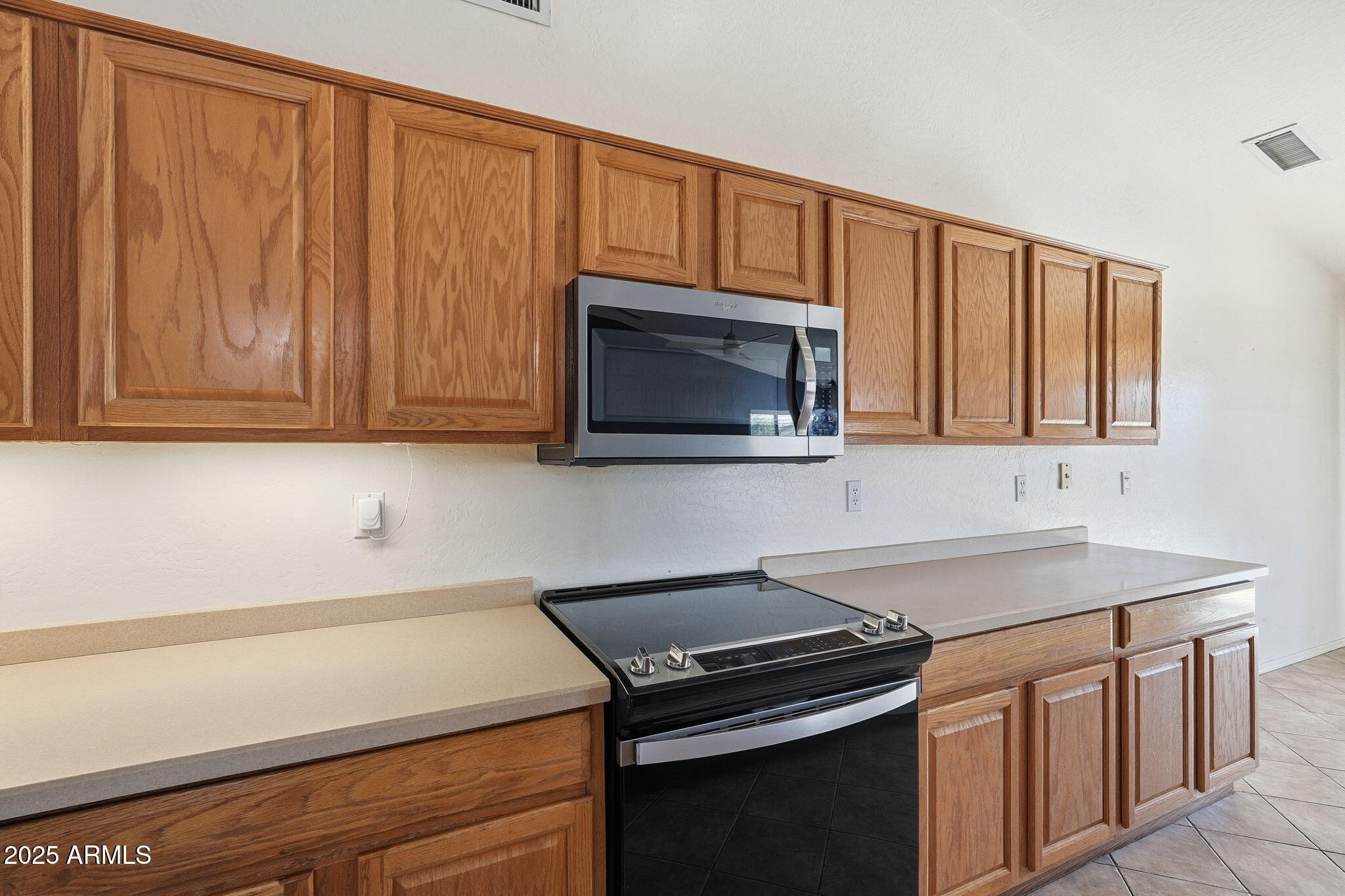 17509 West Rock Ledge Road Goodyear, AZ 85338 - Photo 14 of 55 a kitchen with stainless steel appliances a stove microwave and cabinets