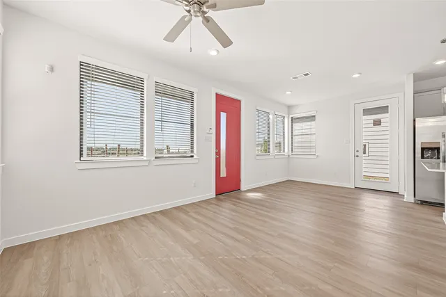 a view of an empty room with a window and wooden floor