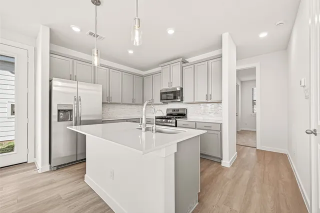 a kitchen with stainless steel appliances granite countertop a refrigerator a sink dishwasher a oven with white cabinets and wooden floor