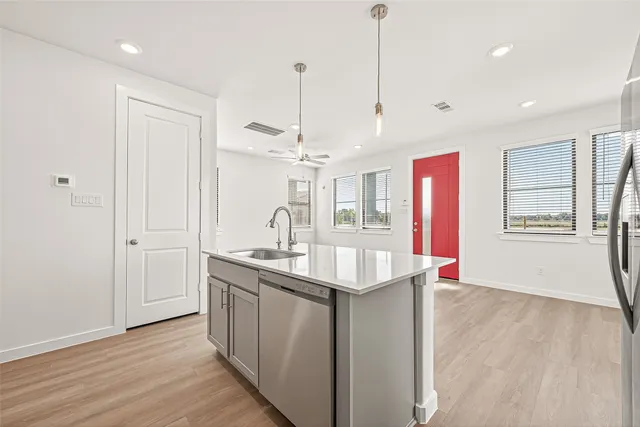 a kitchen with stainless steel appliances granite countertop a sink a window and a chandelier