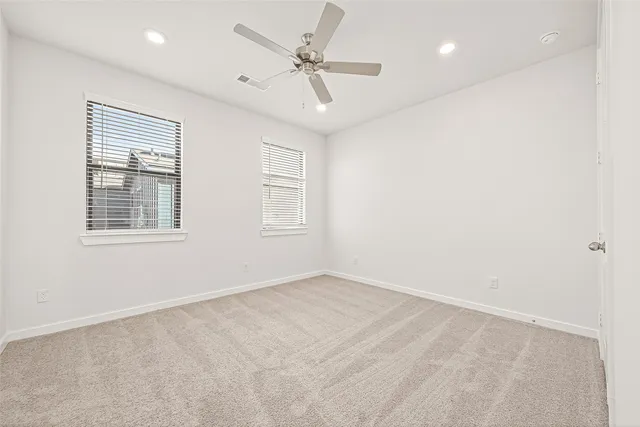 an empty room with windows and fan