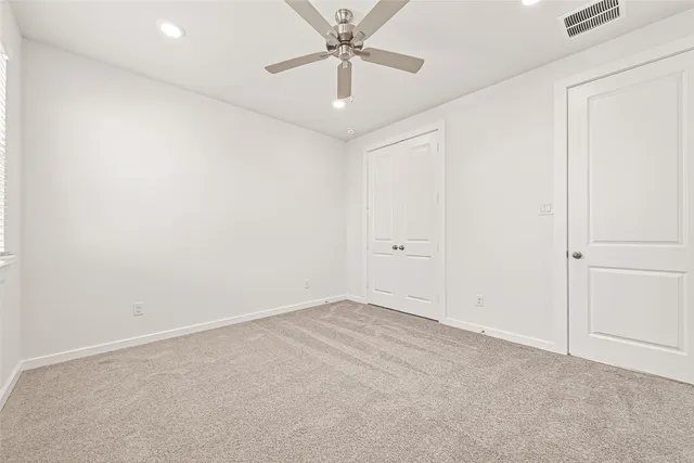 an empty room with a chandelier fan and closet