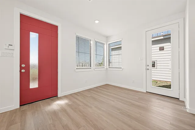 an empty room with wooden floor door and windows
