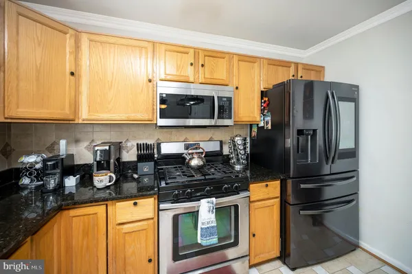 a kitchen with granite countertop stainless steel appliances a stove a refrigerator a sink a counter space and cabinets