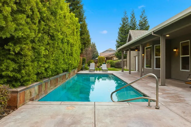a view of yard with swimming pool and trees in the background