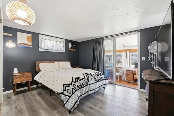 a bedroom with a bed and dresser with wooden floor
