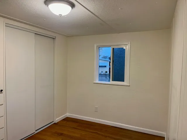 a view of an empty room with wooden floor and a window