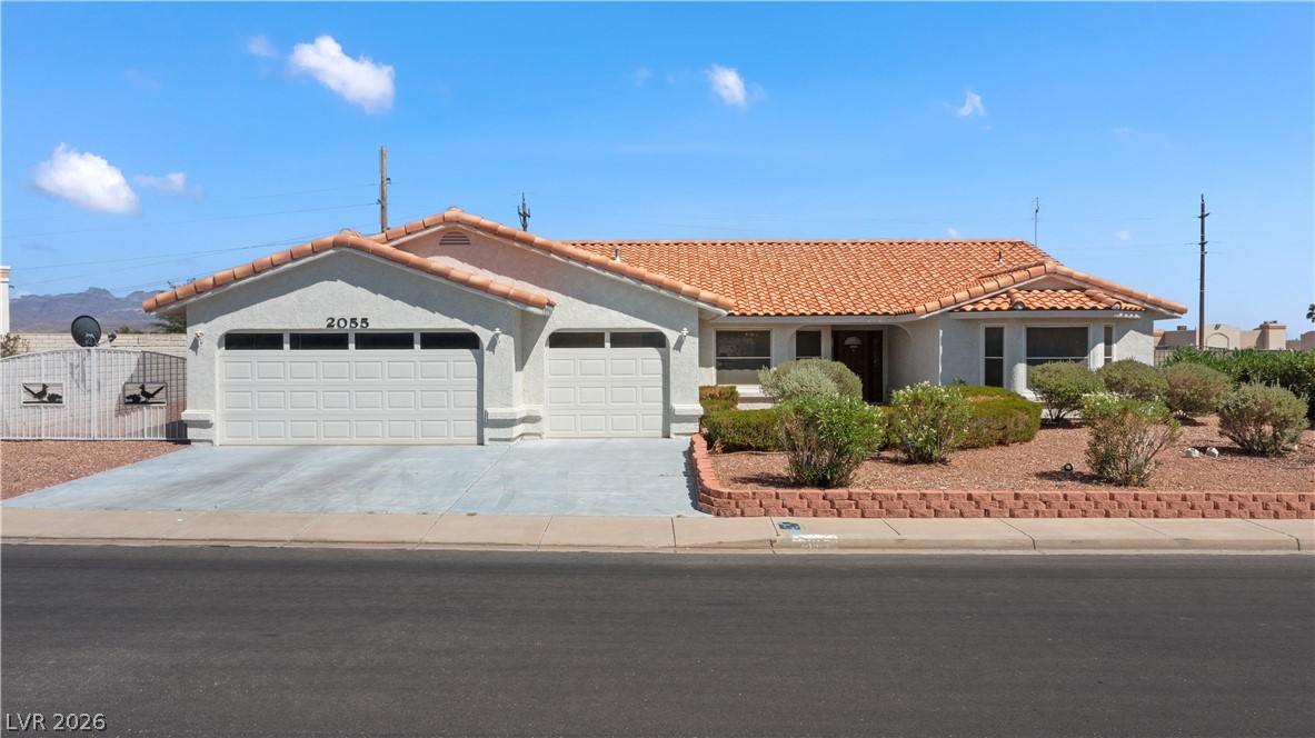 2055 Cholla Way Laughlin, NV 89029 - Photo 64 of 87 A well-kept front yard with mature landscaping and a double-door garage offers inviting curb appeal.