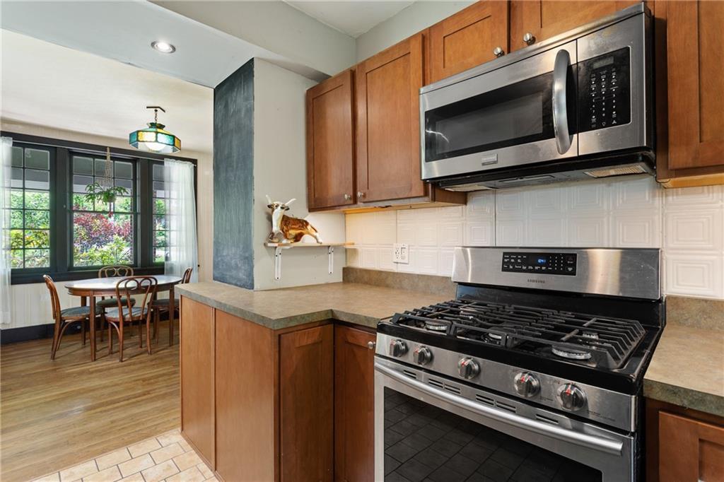 9 Woodside Road Pittsburgh, PA 15221 - Photo 10 of 24 a kitchen with stainless steel appliances a stove a microwave cabinets and a dining table